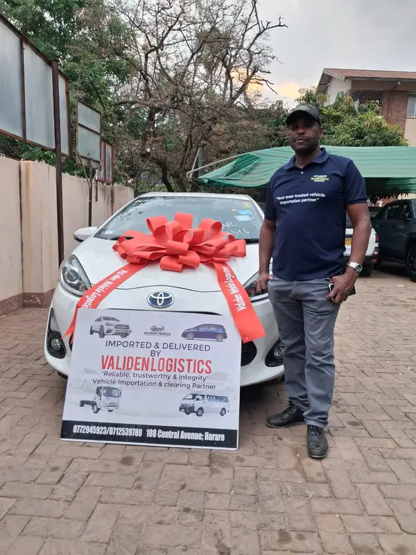 White Toyota hatchback with a red bow and the Validen &ldquo;Imported & delivered&rdquo; board